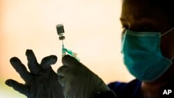 FILE - A syringe is prepared with the Pfizer COVID-19 vaccine at a clinic at the Reading Area Community College in Reading, Penn., on Sept. 14, 2021. 