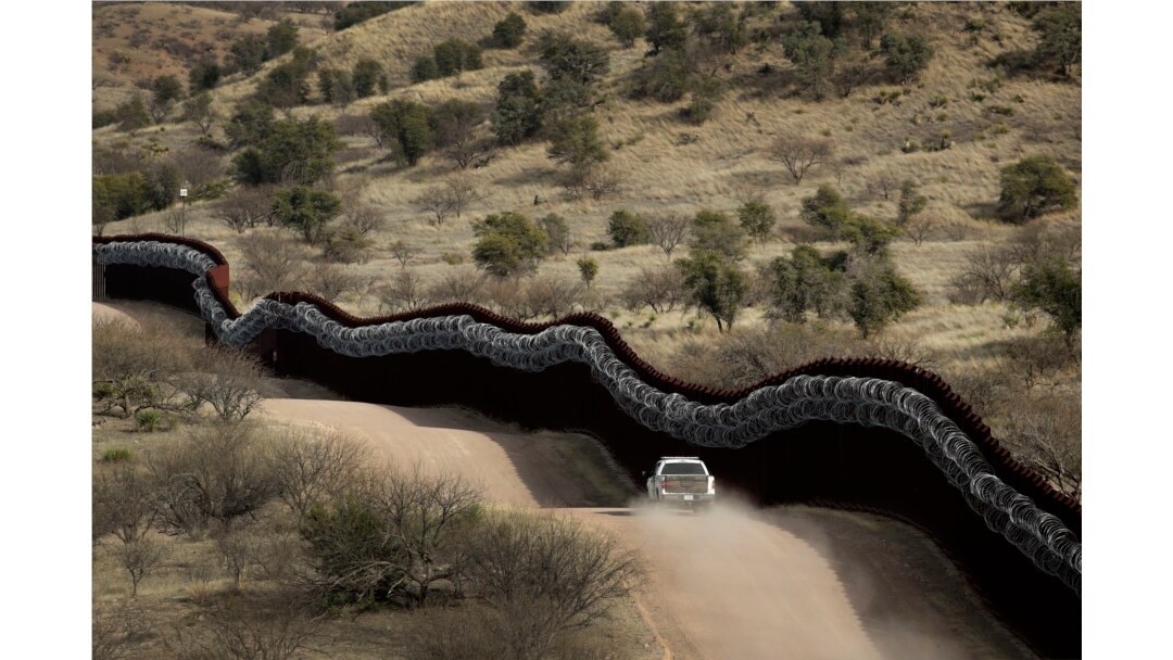 FILE - A Customs and Border Protection agent patrols on the U.S. side of a razor-wire-covered border wall along the southern U.S. border east of Nogales, Ariz., March 2, 2019.