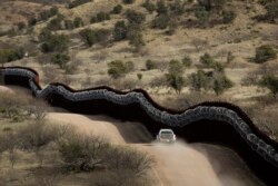 FILE - A Customs and Border Protection agent patrols on the U.S. side of a razor-wire-covered border wall along the southern U.S. border east of Nogales, Ariz., March 2, 2019.