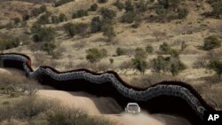 A Customs and Border Control agent patrols on the U.S. side of a razor-wire-covered border wall along the Mexico east of Nogales, Arizona, March 2, 2019.