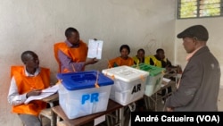 Funcionário de mesa de voto faz demonstração do boletim de voto a eleitor na Beira, Moçambique, 9 outubro 2024