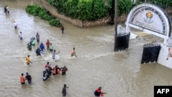 Watembea kwa miguu wakijaribu kupita barabara iliyofurika kufuatia mvua kubwa iliyonyesha katika wilaya ya Kiembeni mjini Mombasa mnamo Novemba 17, 2023.