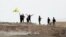 Fighters with the Kurdish People's Protection Units, or YPG, wave their yellow triangular flag on the outskirts of Tal Abyad, Syria, June 15, 2015.