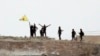 Fighters with the Kurdish People's Protection Units, or YPG, wave their yellow triangular flag on the outskirts of Tal Abyad, Syria, June 15, 2015.