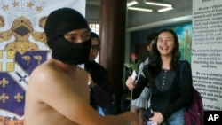 © Student receives rose from protester during naked run to condemn last week's burial of late dictator Ferdinand Marcos at the Heroes' Cemetery, Quezon City, Philippines, Nov. 25, 2016.