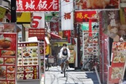 A man wearing a face mask to protect against the spread of the new coronavirus cycles in Yokohama, near Tokyo, May 8, 2020.