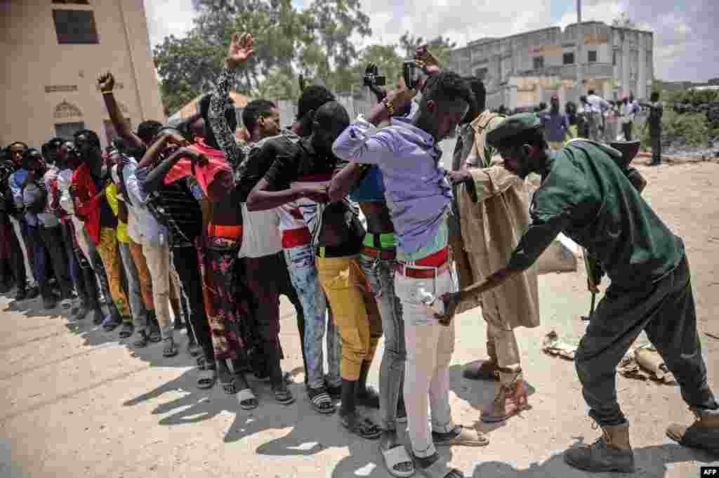 A Somali soldier checks a man at the entrance before a handover ceremony as African Union Mission to Somalia (AMISOM) leaves from the Mogadishu stadium in Mogadishu.