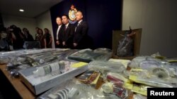 Officers from Police Organized Crime and Triad Bureau (L-R) Chief Inspector Tsue Chun-tung, Chief Superintendent Au Chin-chau and Superintendent Ng Wai-hon, in front of items relating to making explosives seized, at police headquarters in Hong Kong, June 15, 2015. 