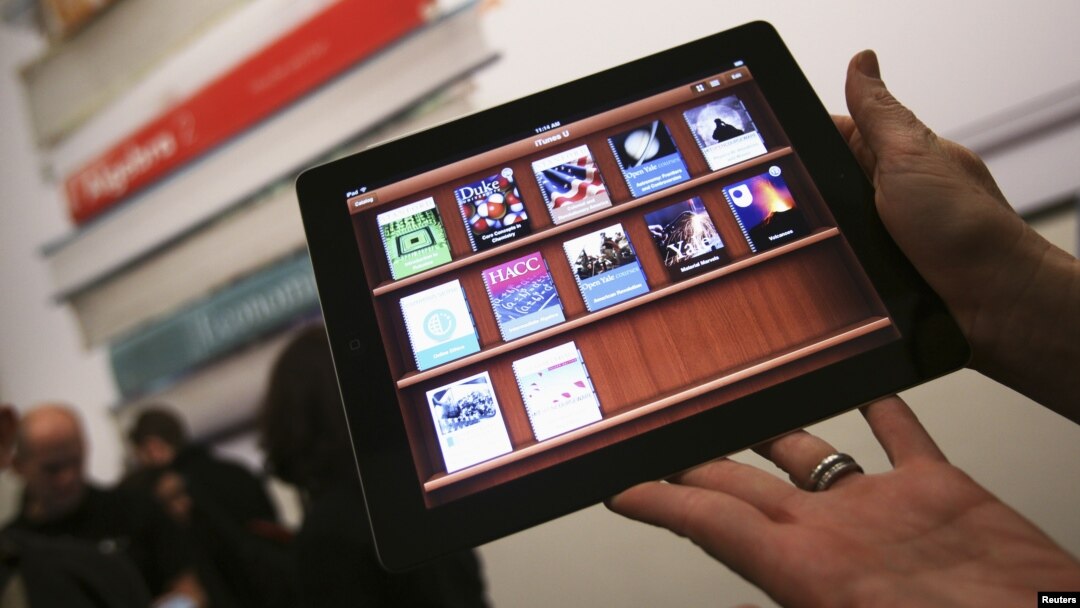 A woman holds up an iPad with the iTunes U app after a news conference introducing a digital textbook service, in New York, January 2012. (file photo)