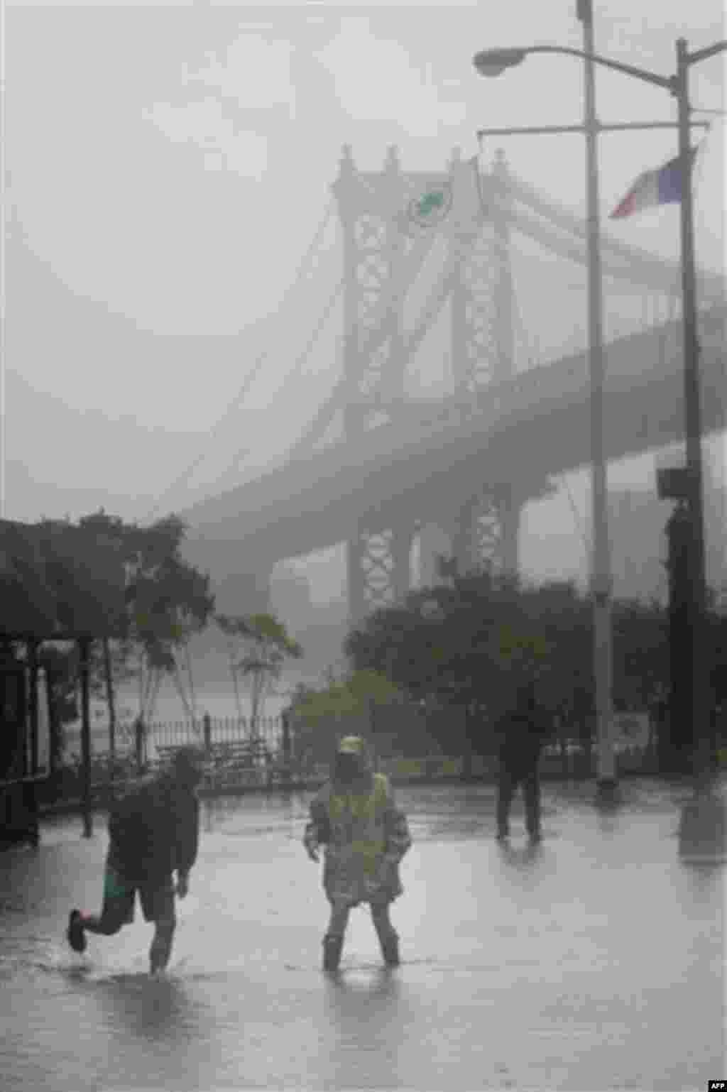 Eddie Lima, left, and Nancy Zakhary wade through a flooded area near the Brooklyn Bridge in New York to take some pictures, Sunday, Aug. 28, 2011. Hurricane Irene bore down on a dark and quiet New York early Sunday, bringing winds and rapidly rising seawa