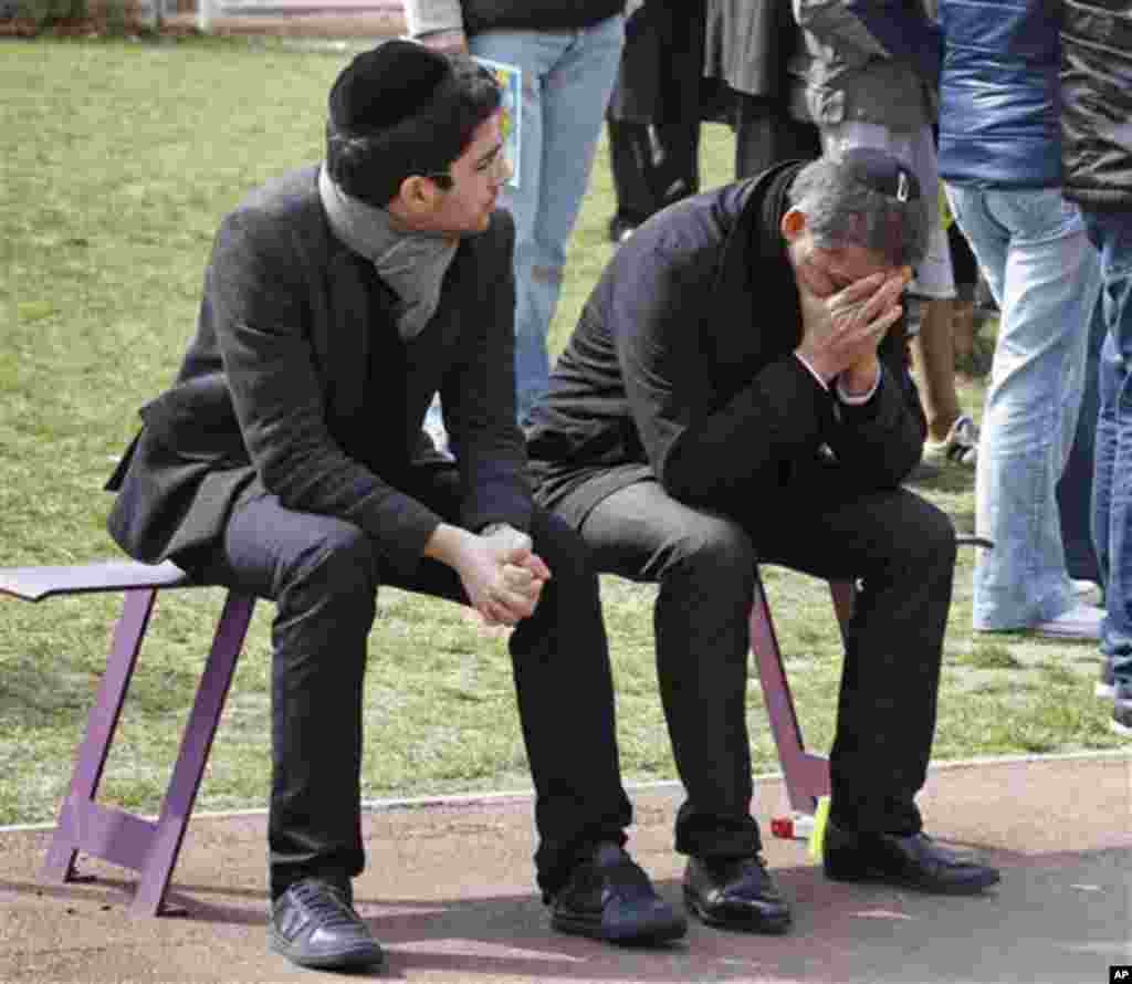 A man is overcome by emotion during a ceremony for the shooting victims at the Ozar Hatorah Jewish school where a gunman opened fire Monday killing four people in Toulouse, southwestern France, Tuesday, March 20, 2012. Police blanketed southern France on 