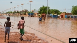 Des enfants marchent dans une rue inondée de Niamey le 15 juin 2017.