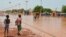 Des enfants marchent dans une rue inondée de Niamey le 15 juin 2017.