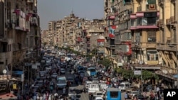 FILE - In this April 14, 2020 photo, people crowd a street a few hours ahead of a curfew in Cairo, Egypt.