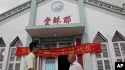 Pastor Tao Chongyin (kiri) bersama anggota gereja Fan Liang'an di depan Gereja Kristen Wuxi bertuliskan "Gereja Yesus" di Longwan, Wenzhou, Provinsi Zhejiang, bagian timur China, 15 JUli 2014 (Foto: dok).