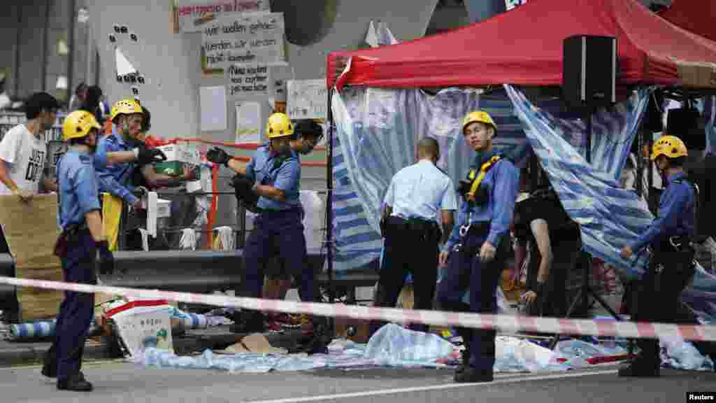 Firefighters remove a tent under a pedestrian bridge as a pro-government supporter threatens to jump off the bridge unless roadblocks set up by Hong Kong pro-democracy protesters are removed in front of the government headquarters in Hong Kong, Oct. 5, 20