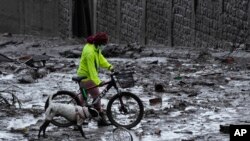 ARCHIVO - Un residente y un perro caminan por una calle llena de lodo después de que una ladera debilitada por la lluvia colapsara y trajera olas de lodo sobre el área de La Gasca en Quito, el 1 de febrero de 2022.