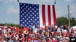 Bendera AS raksasa dikibarkan di belakang para pendukung bacapres dari Partai Republik, Donald Trump, saat kampanye di Butler, Pennsylvania, Sabtu, 13 Juli 2024.(Foto: Gene J. Puskar/AP Photo)