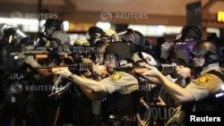 Ajan polis ki pwente zam yo sou manifestan ki tap pwoteste pou yo denonse lanmò pa bal jenn nwa ameriken Michael Brown nan vil Ferguson. (Foto: 18 out 2014).