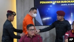 A suspected wanted by China for running a $14 billion investment scam, identified only by his initial LQ, is escorted by Indonesian immigration officers during a news conference in Jakarta, Indonesia, Oct. 10, 2024.