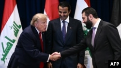 لەم دیمەنەدا سەرۆک دۆناڵد ترامپ تەوقە لەگەڵ سەرۆکی سوریا ئەحمەد شەرع دەکات و ئەمیری قەتەر شێخ تەمیم بن حەمەد لە نێوانیاندا وەستاوە. دیمەنەکە دەگەڕێتەوە بۆ بەرواری 22ـی نۆی 2026 لە پەراوێزی کۆبوونەوەی گشتی نەتەوە یەکگرتووەکان لە نیویۆرک. 