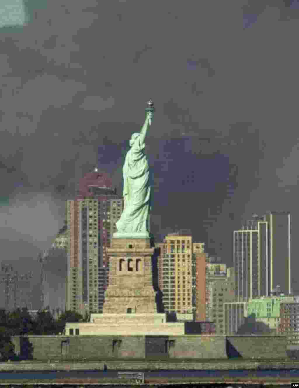 Thick smoke billows into the sky from the area behind the Statue of Liberty where the World Trade Center towers stood Tuesday, Sept. 11, 2001. The towers collapsed after terrorists crashed two planes into them Tuesday. (AP Photo/Daniel Hulshizer)