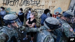 National Guard personnel return to their defensive position as protesters make room for them to fall back following a confrontation on East Lake Street, May 29, 2020, in St. Paul, Minn. 