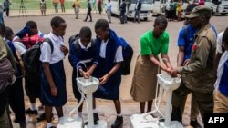 Secondary school students wash their hands at a temporary hand washing point, March 16, 2020. The Rwandan government decided to send home all students of boarding schools after the first case of COVID-19 was found Friday in Kigali, Rwanda.
