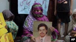 Pakistan Execution: Safia Bano displays the picture of her husband Imdad Ali, a death row prisoner, while she sits with other family members in Burewala, in central Pakistan, Sunday, Sept. 18, 2016. 