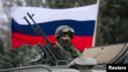 FILE - A Russian flag is seen behind a Russian army vehicle outside a Ukrainian border guard post in the Crimean town of Balaclava March 1, 2014.