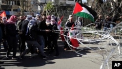 Protesters try to remove barbed wires that block a road leading to the U.S. Embassy during a protest is held against the proposed peace deal for the Middle East by President Donald Trump, in Aukar, east of Beirut, Lebanon, Feb. 2, 2020. 