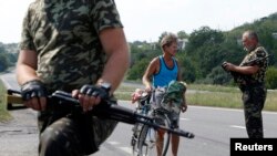 Armed pro-Russian separatists stop a resident at a checkpoint outside Donetsk, Aug. 5, 2014.