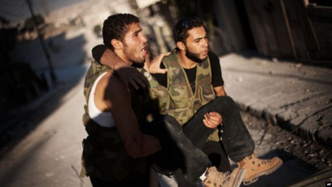 Hai người lính thuộc phe nổi dậy Syria giúp một người bị thương trong quá trình chiến đấu ở Izaa, huyện Aleppo, Syria, 7/9/2012