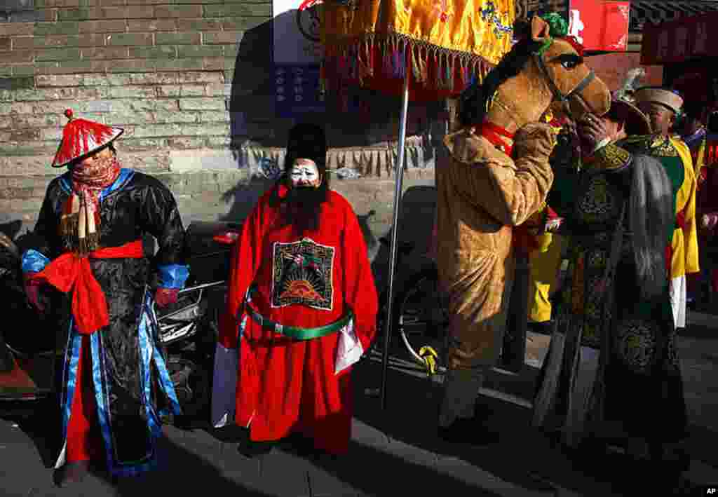 A performer wearing a horse costume (2nd R) stands next to fellow actors dressed in traditional costume and wearing make-up as they prepare to take part in Chinese new year celebrations at the 700-year-old Dongyue Temple in Beijing, January 23, 2012. (Reu