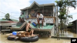 Residents use an improvised raft for transport as floodwaters continue to inundate their homes at Calumpit township, Bulacan province, north of Manila, Philippines, Monday, Oct. 3, 2011.