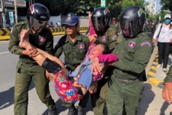 A woman is carried by police officers after security guards broke up a small protest near the Chinese embassy opposing alleged plans to boost Beijing's military presence in the country, in Phnom Penh, Cambodia October 23, 2020. (REUTERS/Heng Mengheang)