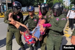FILE - A woman is carried by police officers after security guards broke up a small protest near the Chinese embassy opposing alleged plans to boost Beijing's military presence in the country, in Phnom Penh, Cambodia October 23, 2020. (REUTERS/Heng Mengheang)