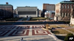 FILE - A woman walks on the Columbia University campus, March 9, 2020, in New York. 