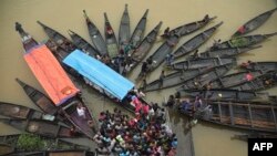 People gather to collect food aid in a flooded area following heavy monsoon rainfalls in Companiganj, Bangladesh.