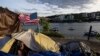 FILE - Frank, seorang tunawisma, duduk di dalam tendanya di Portland, Oregon di tepi Sungai Willamette, 5 Juni 2021. (AP/Paula Bronstein, File)