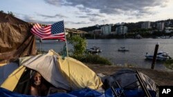 FILE - Frank, seorang tunawisma, duduk di dalam tendanya di Portland, Oregon di tepi Sungai Willamette, 5 Juni 2021. (AP/Paula Bronstein, File)