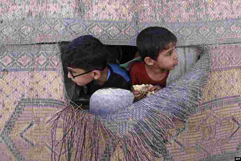 Boys peek out of a torn mat at the al-Shati camp for Palestinian refugees in Gaza City.