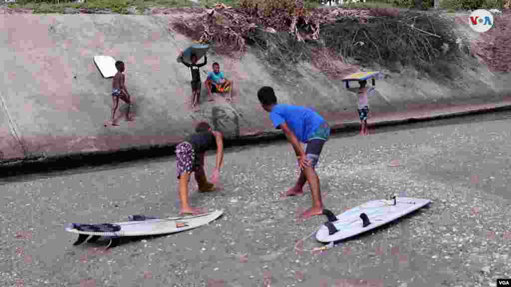 Calentamiento, ejercicios de estiramiento, algo que los niños hacen cada mañana antes de lanzarse a meterse entre las olas con sus tablas de surf. [Foto: VOA / Nicole Kolster].