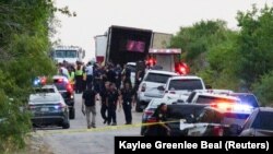 Полицейские у грузовика, в котором были обнаружены десятки тел погибших