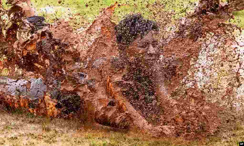 A boy jumps in a puddle of muddy water as he enjoys the rains in Mumbai, India, June 27, 2022.