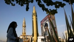FILE - A Ghadr-H missle, center, a solid-fuel surface-to-surface Sejjil missile and a portrait of the Supreme Leader Ayatollah Ali Khamenei are on display at Baharestan Square in Tehran, Iran, Sept. 24, 2017.