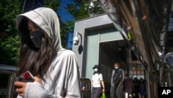 Commuters wearing face masks walk out of a subway station in the central business district in Beijing, July 7, 2022.