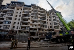 Servicemen work at the scene at a residential building following explosions, in Kyiv, Ukraine, June 26, 2022.