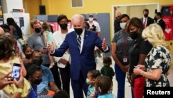 U.S. President Joe Biden greets children with first lady Jill Biden (right) at a COVID-19 vaccination clinic hosted by the District of Columbia's Department of Health at the Church of the Holy Communion in Washington, June 21, 2022.