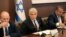 Israeli caretaker Prime Minister Yair Lapid, center, sits next to former Prime MInister Naftali Bennett, left, as he chairs the first cabinet meeting days after lawmakers dissolved parliament, in Jerusalem, July 3, 2022.
